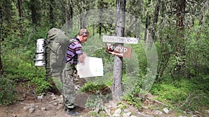 Tourist with a map near the signs. Inscriptions Tungur village, Kara Turek mountain.