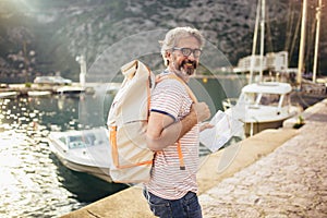 Tourist mature man standing with map and backpack near the sea