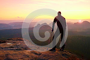 Tourist with medicine crutch on mountain peak. Deep misty valley bellow silhouette of ma