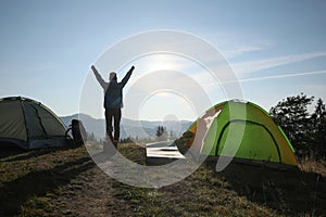 Tourist in mountain camping on sunny day, back view