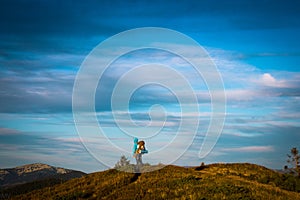 Tourist on Mountain ridge. Man with backpack hiking. Silhouette on blue sky background. Seasonal photo in cold tones