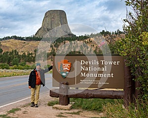 A tourist next the sign of Devils Tower National Monument in Wyoming