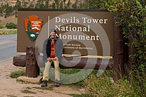 A tourist next the sign of Devils Tower National Monument in Wyoming