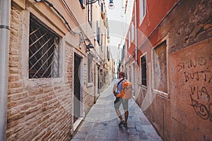 Turista arancia zaino un passeggiate lungo stretto strade Europa. estate. facciata da vecchio case 