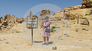 Tourist with painted steel sign for Gebel Al Mawta, the `Mountain of the Dead`, in Siwa Oasis, Egypt.