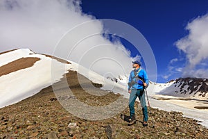 Tourist photographer examines the top of a snow-covered mountain and prepares to climb