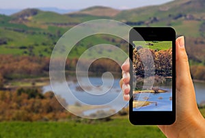 Tourist photographing Pozzillo lake and volcano Etna with smartphone