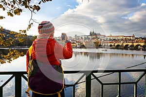 Tourist photographing Prague with Charles Bridge and Hradcany