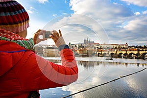 Tourist photographing Prague with Charles Bridge and Hradcany