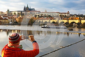 Tourist photographing Prague with Charles Bridge and Hradcany