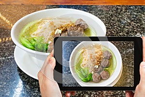 tourist photographs meat balls with noodle soup