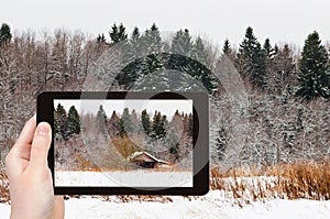 Tourist photographs wooden house in snowed forest