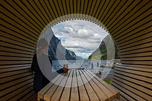 Tourist by the picnic table - Young woman drinks coffee while enjoying beautiful view of lysefjorden