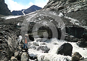 Tourist with a piece of an ice on a background of a thawing glacier in Altay mountains