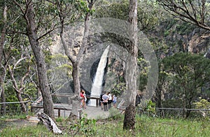 Tourist on platform looking at waterfall in flood.