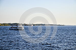 Tourist pleasure boat floats on the river Dnipro in the city Zaporizhya at sunset