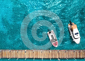 Tourist pleasure yacht and motor boat on the sea near the pier. Top view