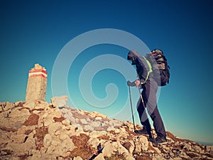 Tourist with poles and backpack walk to mountain peak. Last step to summit