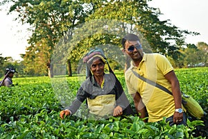 Tourist poses with a Tea worker who pick up tea leafs by hand at tea garden in Darjeeling