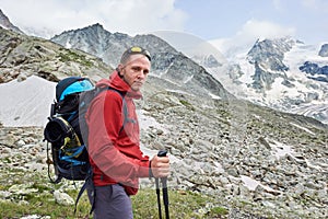 Tourist posing using trakking sticks, mountains on background.