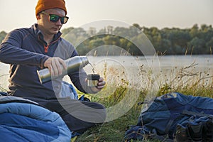 A tourist pours tea from a thermos