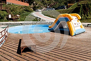 A tourist recreation center with a children`s pool with blue clear water, an inflatable slide and wooden sun loungers. Rest,