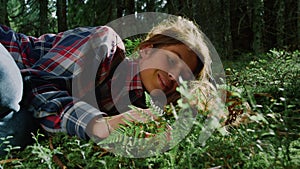 Tourist relaxing on grass in summer forest. Young woman lying on ground in woods