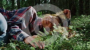 Tourist relaxing on grass in summer forest. Young woman lying on ground in woods