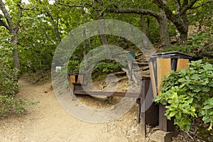 Tourist resting place, route in a mountain forest, a bench with a trash can