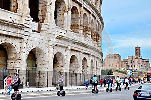 Tourist Rides Electric Scooter Segway on the street past the Coliseum in Rome.