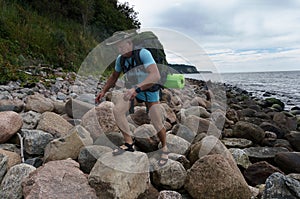 A tourist on a rocky beach, Baltic sea, a man with a backpack walks over rocks