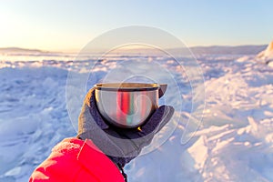 Tourist`s hand holding a steaming mug or cup with hot tea or coffee in winter landscape outdoors. Winter and rourism concept