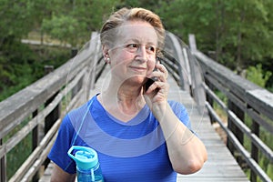 Tourist senior woman using cell smart phone call smile summer vacation green tree park travel communication