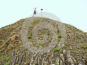 Tourist on sharp basalt peak of volcano formation