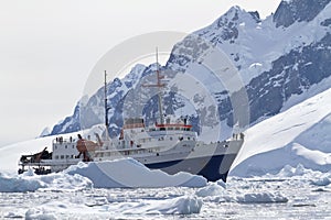 tourist ship among the icebergs on the background of the mountains of the Antarctic Peninsula