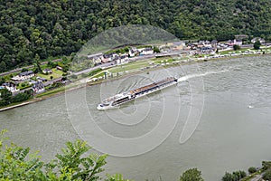 A tourist ship sailing on the river Rhine in western Germany, visible buildings and caravans on the river bankv.