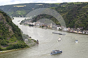 Tourist ships and barges sailing on the river Rhine in western Germany, visible buildings and hills.