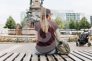 A tourist sitting on a bench in a city park in Leipzig in Germany.