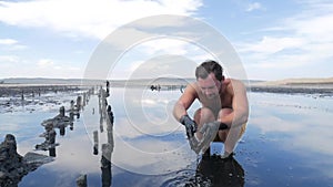 Tourist Sitting in Black Medical Mud Pond with Salty Water. HD Slowmotion.