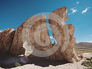 Tourist sitting on large Andes mountains Altiplano stone rock formation in Valle de Rocas Uyuni Sur Lipez Potosi Bolivia
