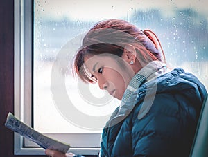 Tourist sitting on a train reading Map and Tourist information while rain puring at the windows