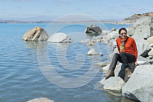 Tourist sitting by turquoise blue water of snow feed scenic Lake Pukaiki