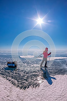 Tourist with sleds walks along the blue ice of Lake Baikal
