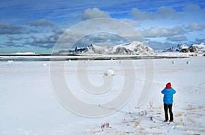 Tourist on the snowy beach  admiring the landscape in Lofoten Archipelago.
