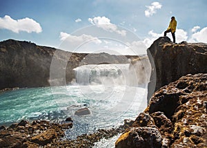 Tourist is standing on a cliff near a waterfall, the concept of