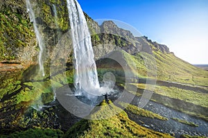 Tourist standing in front of Seljalandsfoss with rainbow around , beautiful amazing landscape from Iceland,