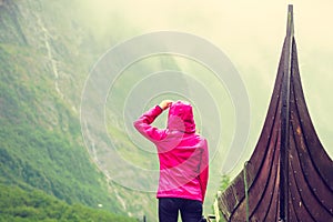 Tourist standing near old wooden viking boat in norwegian nature