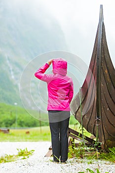 Tourist standing near old wooden viking boat in norwegian nature