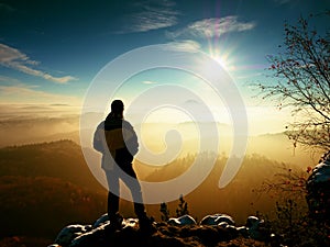 Tourist standing on rocky view point and watching into misty valley.