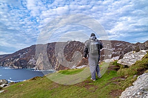 Tourist standing at Slieve League Cliffs which are among the highest sea cliffs in Europe rising 1972 feet above the